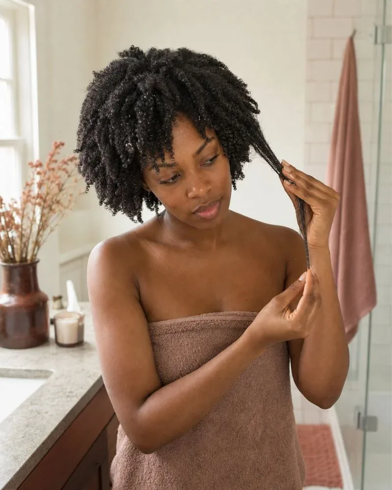 Woman assessing a damp section of her Type 4 natural hair