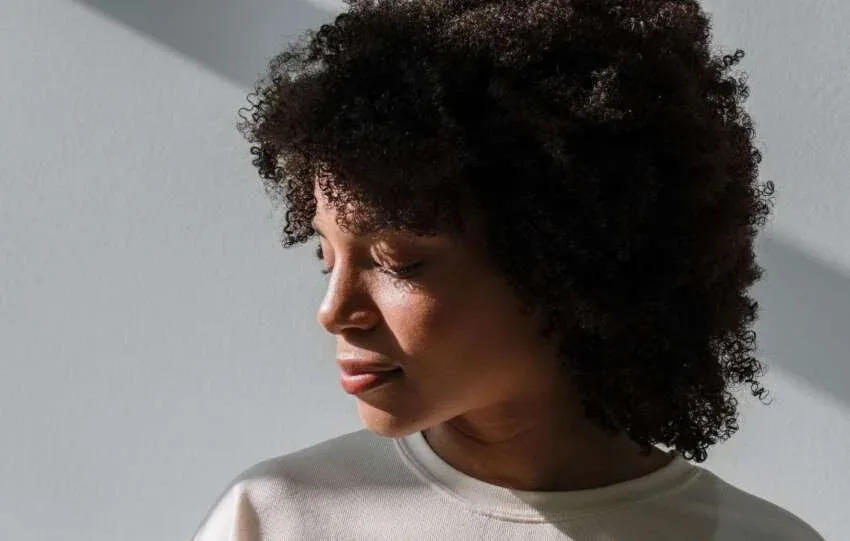 Woman with full natural hair photographed in soft window light.