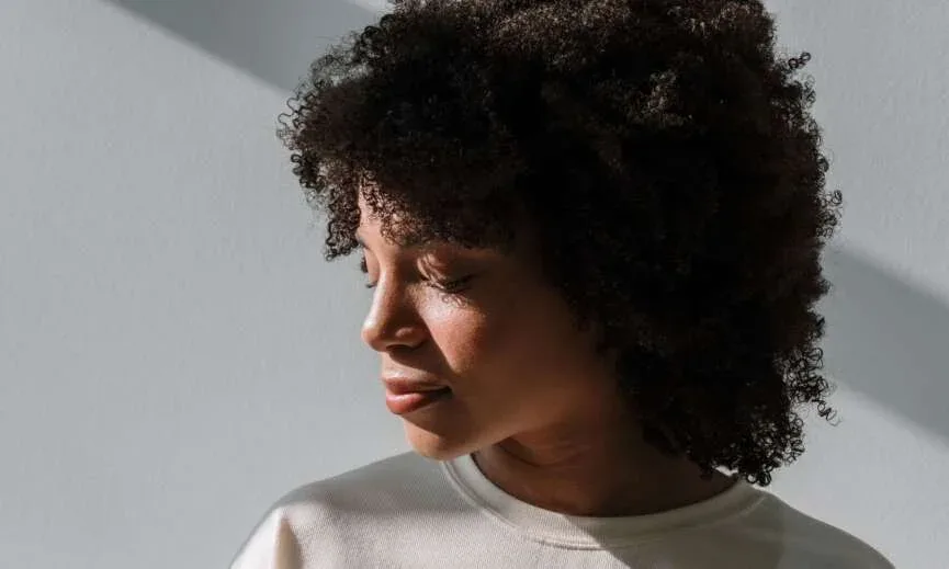 Woman with full natural hair photographed in soft window light.