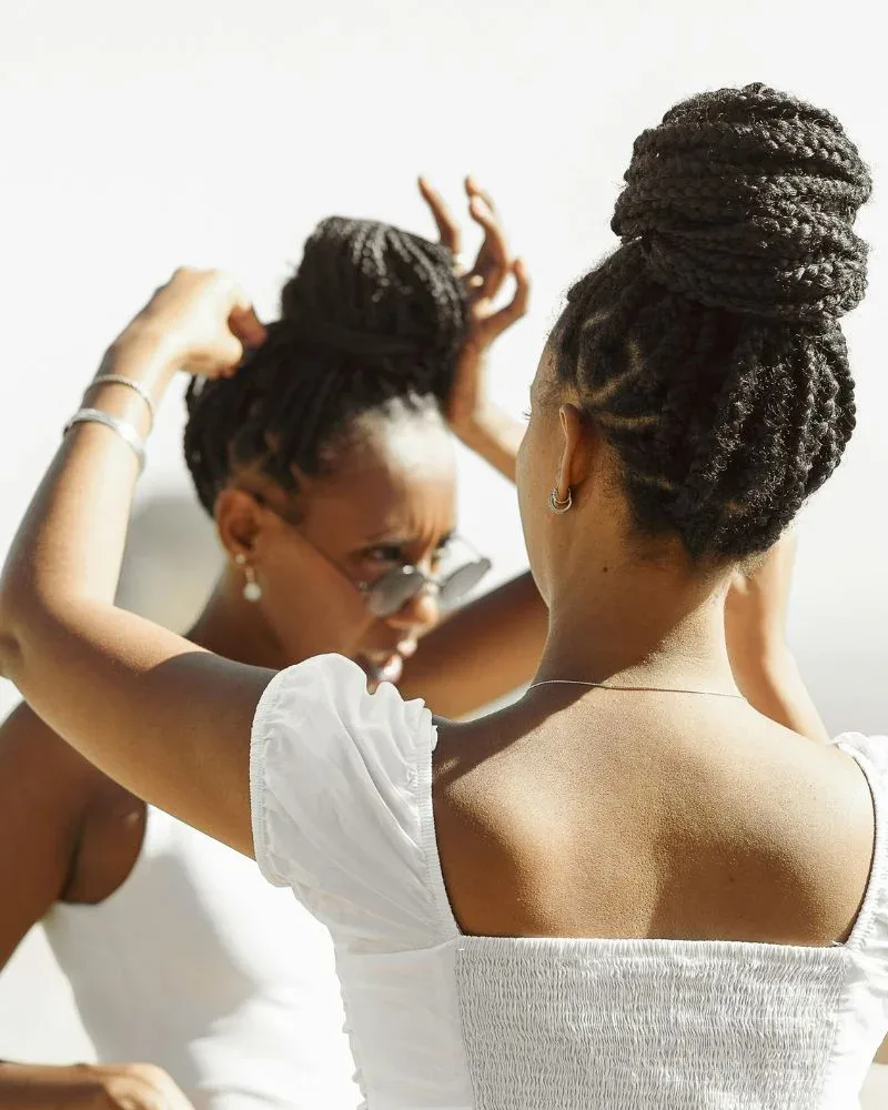 woman touching scalp with braids showing tension, irritation and braid bumps