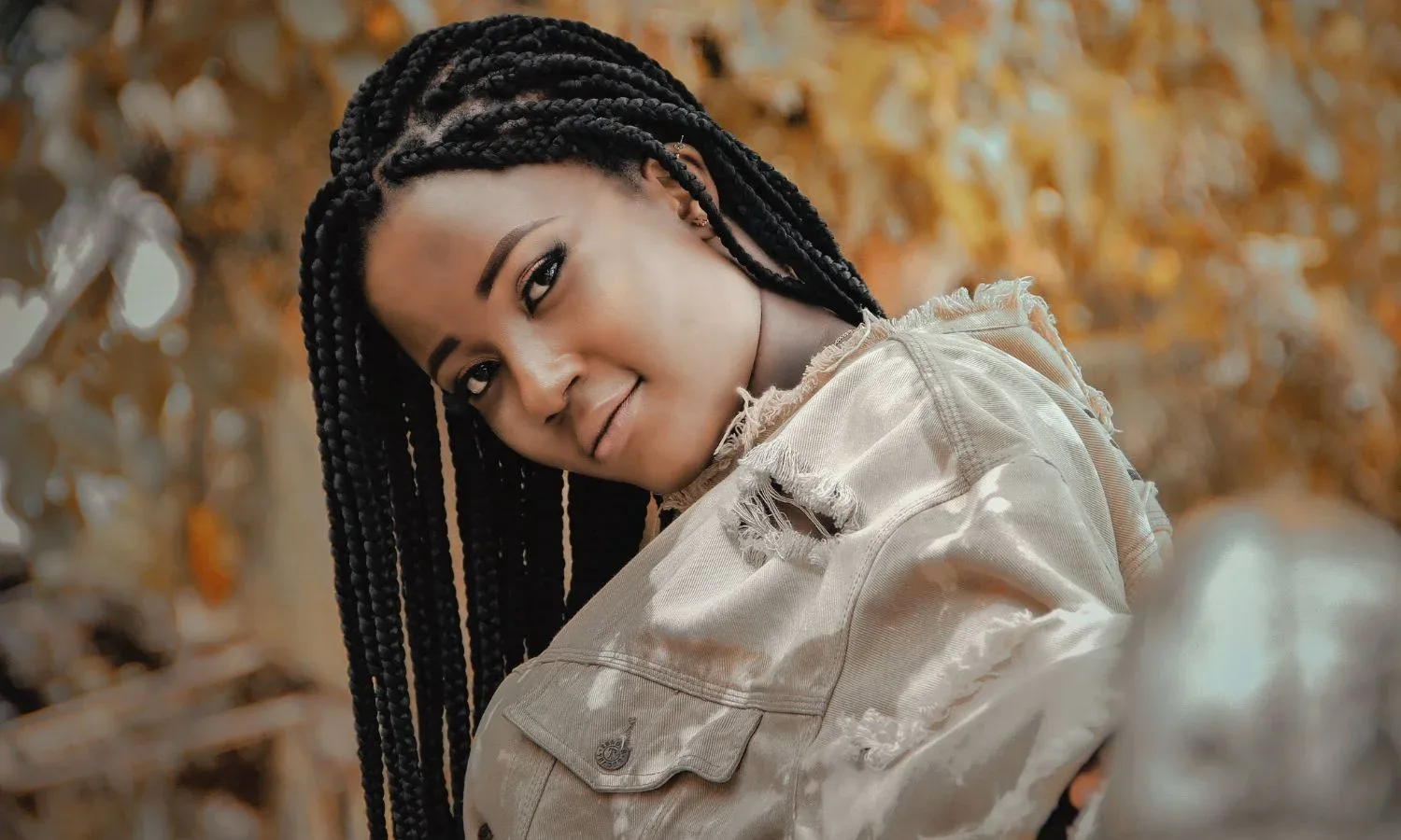 Black woman wearing medium box braids outdoors.