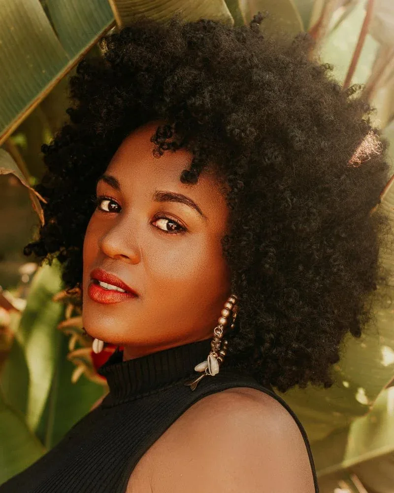 Woman wearing her natural coily hair in a full style