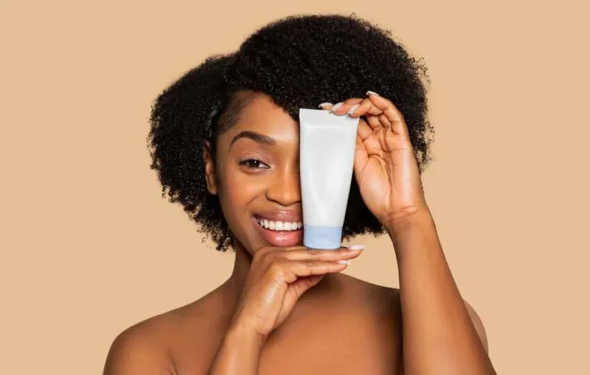 Woman holding a moisturizing hair product for healthy 4C natural hair.