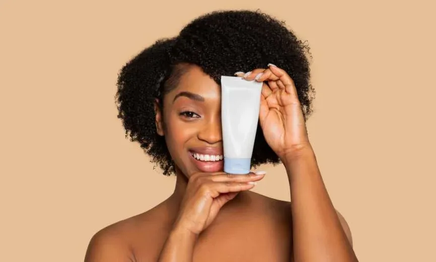 Woman holding a moisturizing hair product for healthy 4C natural hair.