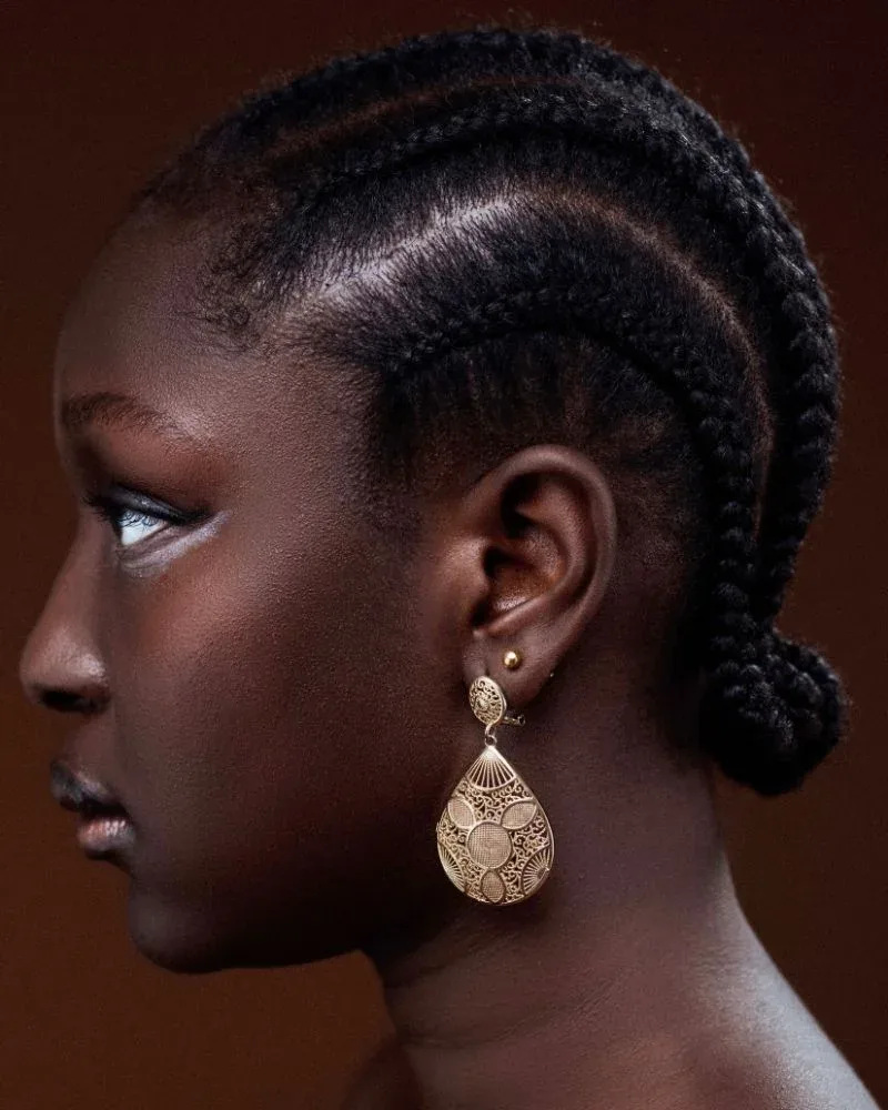 Black woman wearing cornrows styled into a low braided bun
