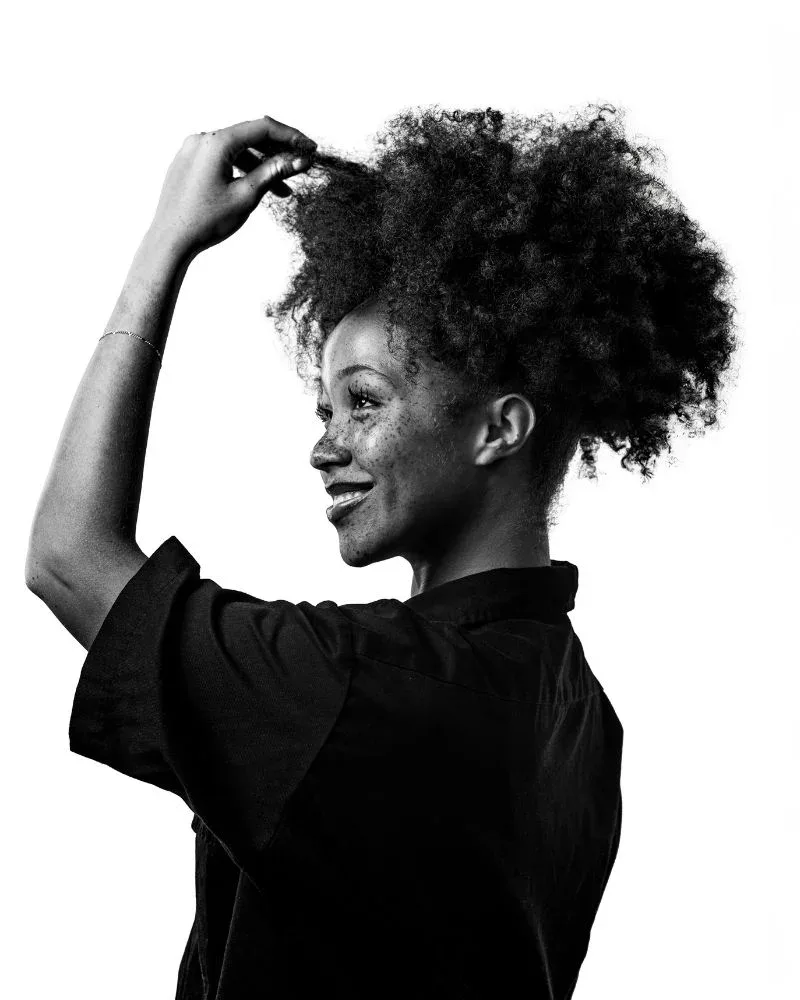 woman stretching natural hair strand showing curl structure and tension