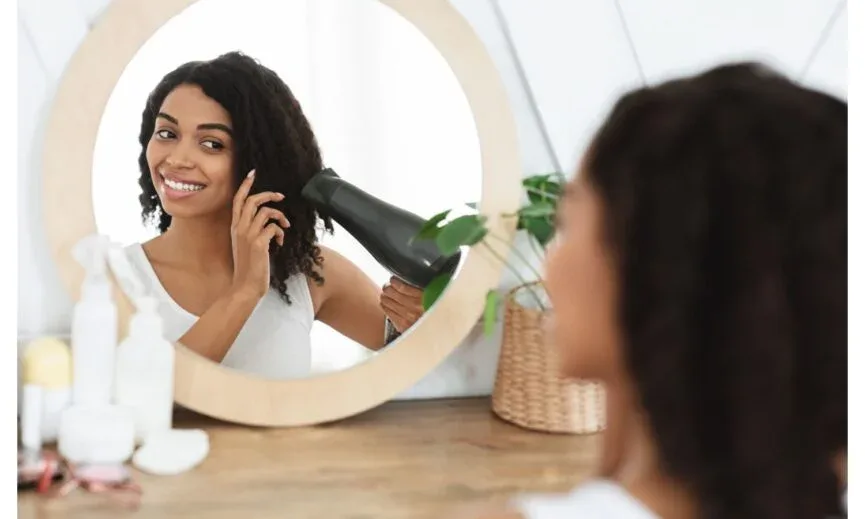 Black woman blow drying natural hair using heat protectant