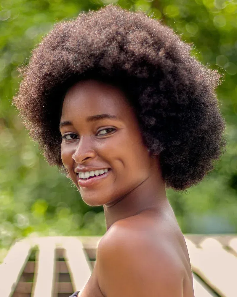 Woman with tightly coiled 4C natural hair with high shrinkage and volume.