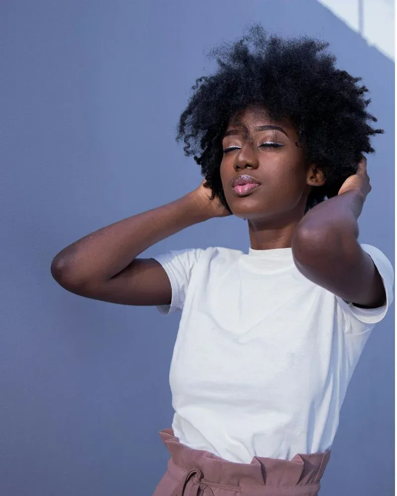 Woman touching natural hair showing signs of product buildup
