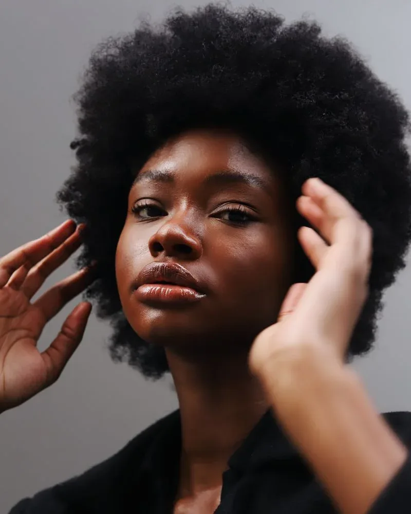 Woman with healthy natural 4C afro highlighting the results of a consistent haircare routine