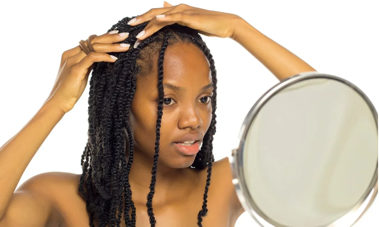 Woman with twists touching her roots while looking in a mirror.