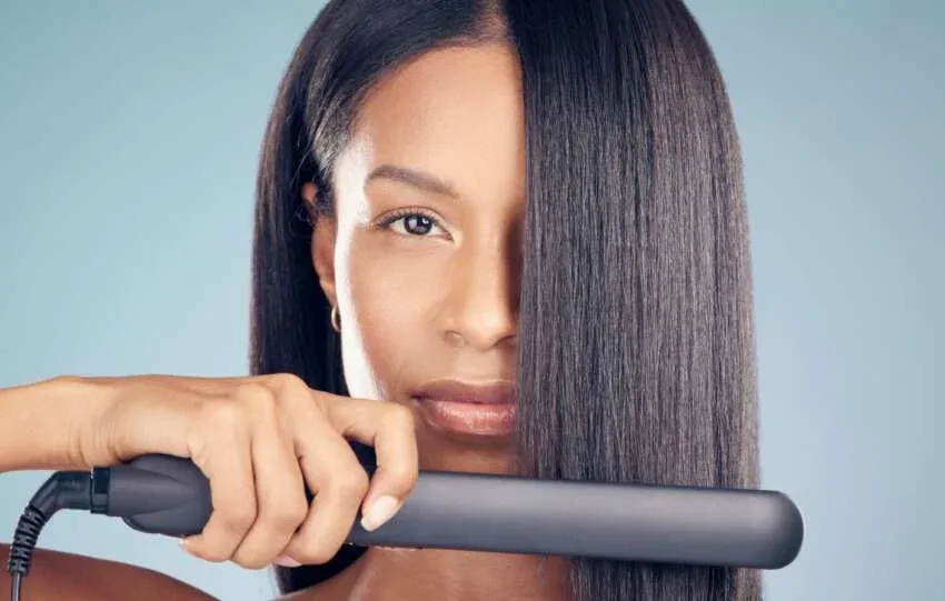 Woman using a flat iron to achieve silk press on natural hair